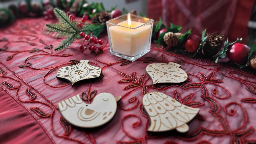 Adornos de navidad hechos de madera sobre mesa con decoración navideña y vela encendida