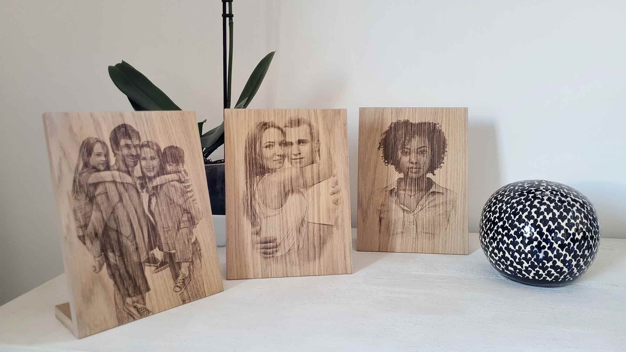 fotografía bodegón con diversos grabados en madera con peana junto a una planta y objeto decorativo cerámico