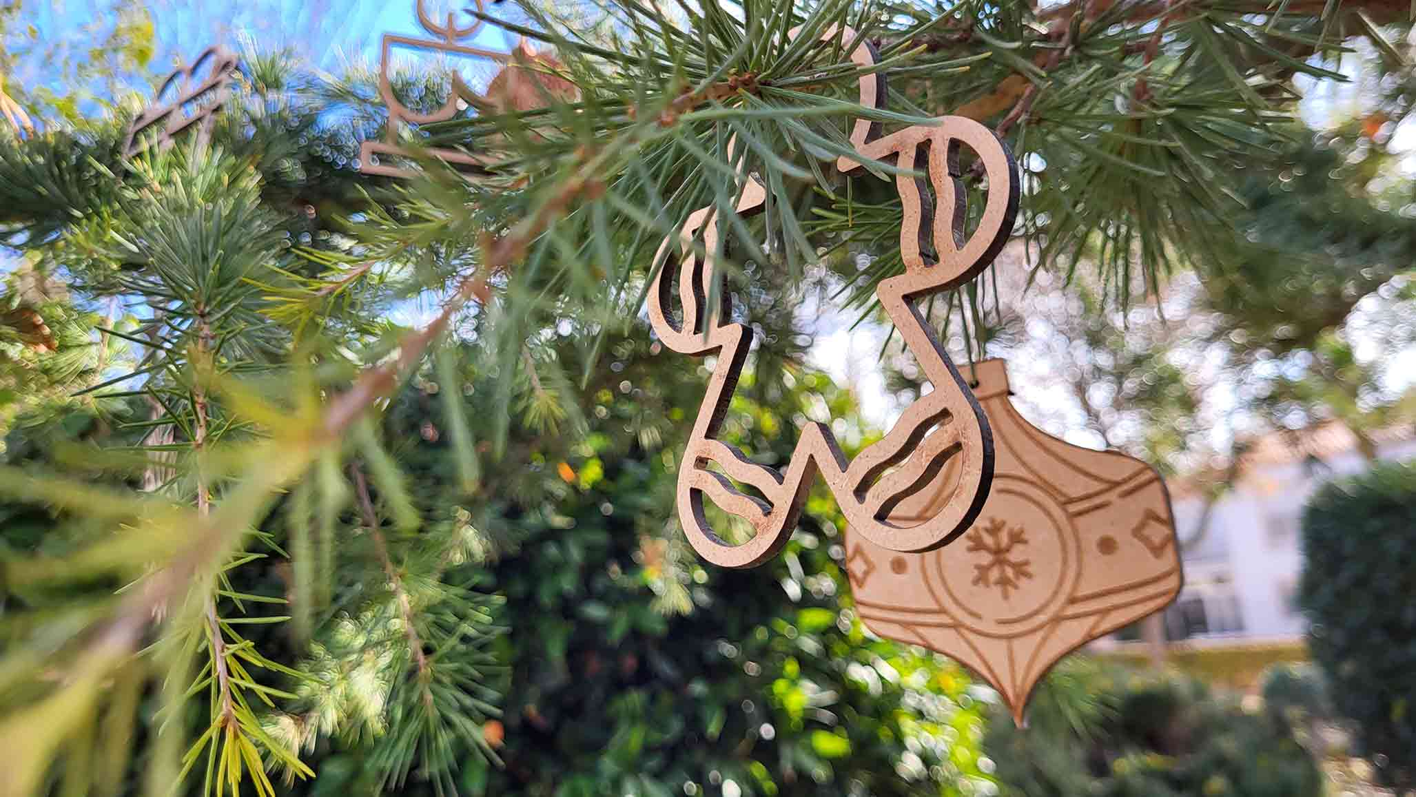 Adornos de navidad de madera colgando de las ramas de un arbol natural