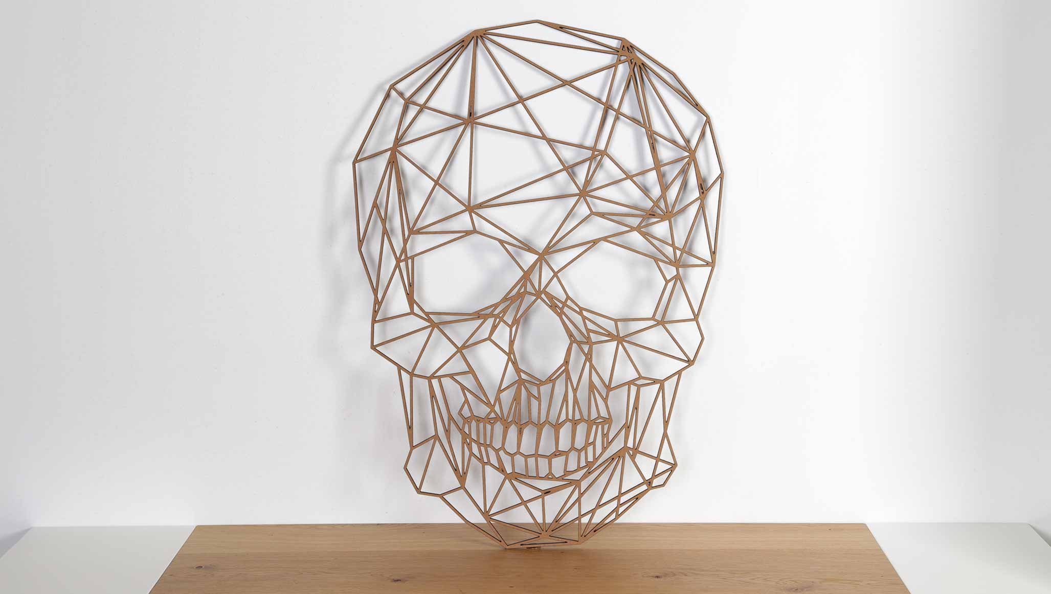 decoración con figuras geométricas de madera. Fotografía de calavera de madera decorativa con diseño geométrico sobre una mesa.