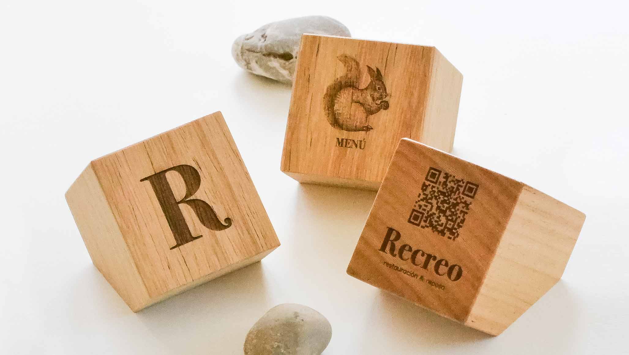 imagen con varios cubos y prismas con grabado a láser de logotipos y códigos qr