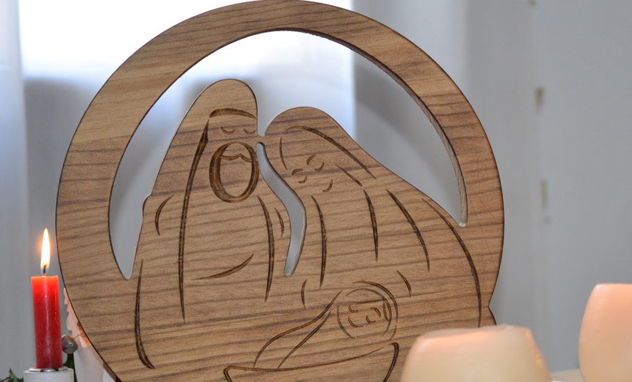 imagen de decoración navideña con detalle de belén en madera y vela encendida de color rojo