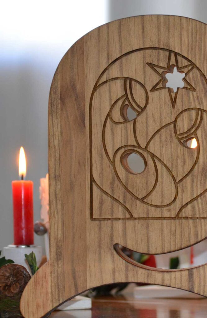 detalle de belen de madera de navidad con grabado minimalista y vela decorativa